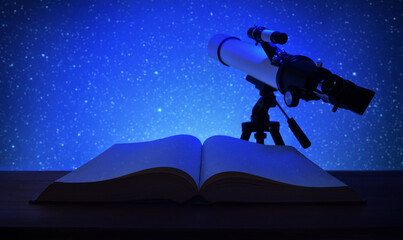 Studying stars with book and telescope focusing blue sky