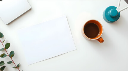 Overhead view of white desk with coffee cup, paper and a modern teal desk lamp