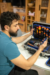 Man searches and organizes his toolbox, looking internet tutorial