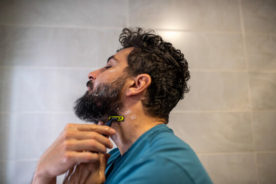 Man shaving beard at home bathroom