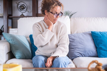 Mature woman feeling sad and overwhelmed at home. Middle-aged female sitting alone with negative...