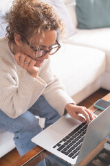 Middle-aged woman working from home on laptop. Mature female freelancer showing different facial...