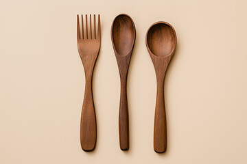 Three wooden cutlery items on a beige background, Three wooden utensils, Three wooden utensils on a beige background.