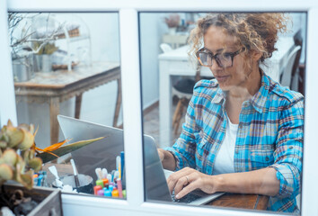 Mature woman working remotely from home using laptop computer. Middle-aged freelancer or remote...