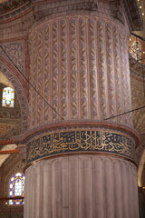 A grand, ornately decorated interior column in a mosque, featuring vertical floral motifs and a...