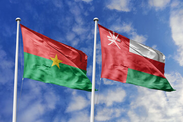 A Burkina Faso and Oman flag, a metaphor for Middle East-African ties, wave together against a blue sky, symbolizing friendship and cultural exchange.
