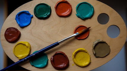 A wooden palette with multiple circular blobs of paint in various colors