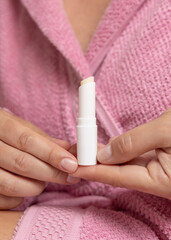 Woman in pink bathrobe holding in hands opened lip balm stick closeup, girly cosmetic mockup