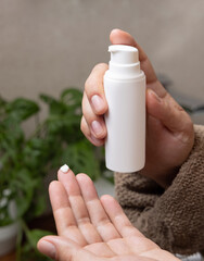 Woman in brown bathrobe with a white cream bottle in hand in bathroom closeup, cosmetic mockup