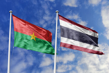 A Burkina Faso and Thailand flag, a metaphor for East-West connection, wave together against a blue sky, symbolizing friendship and cultural exchange.
