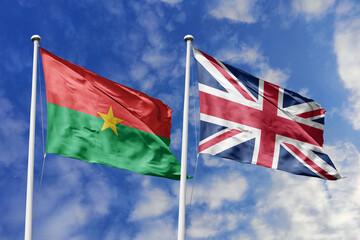 A Burkina Faso and UK flag, a metaphor for historical links, wave together against a blue sky, symbolizing friendship and global partnership.