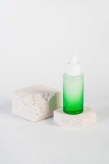 Green glass cosmetic bottle, Skin care or sunscreen cosmetic with stylish props on white background.
