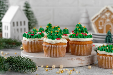 Christmas tree and wreath shaped cupcakes with candy sprinkles on top. Christmas dessert on a light concrete background.