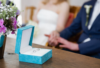 Close up of a blue box with two silver wedding rings on a wooden table, blurred background 