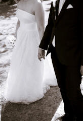 Close up of bride and groom holding hands and walking outdoors