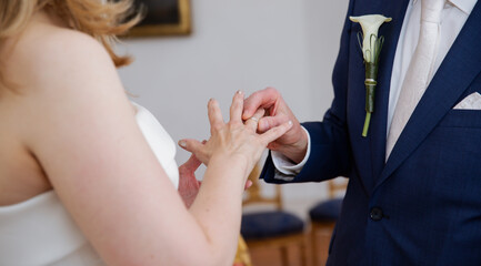 Close up of grooms hand putting a ring a bride hand, getting married 