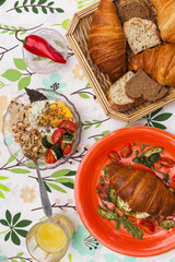 Homemade croissant sandwich with avocado, poached egg, bacon, arugula, and cherry tomatoes. A stylish brunch with a child enjoying the meal