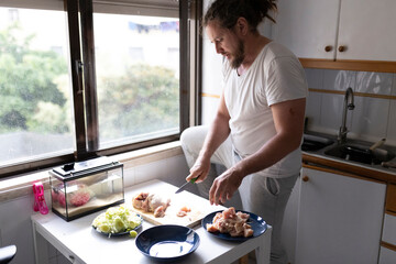 Man cutting chicken meat on kitchen table, preparing meal