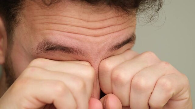 Caucasian man rubbing his tired eyes with his hands