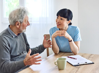 Doctor or nurse caregiver with senior couple at home or nursing home