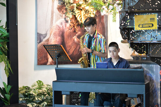 Young man playing saxophone and  piano smiling at a restaurant table