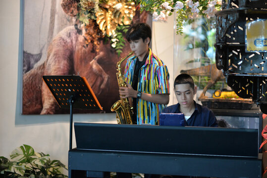 Young man playing saxophone and  piano smiling at a restaurant table