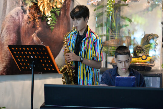 Young man playing saxophone and  piano smiling at a restaurant table