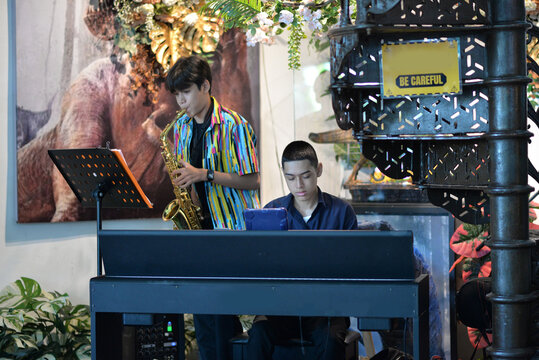Young man playing saxophone and  piano smiling at a restaurant table