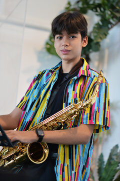 Teenager boy playing saxophone musician standing in the restaurant 