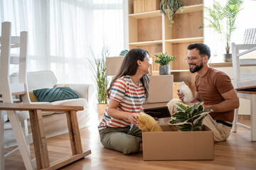 Happy couple unpacking belongings in new home after moving in
