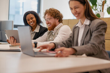 Three dedicated professionals engaged in productive teamwork while utilizing laptops and tablets...
