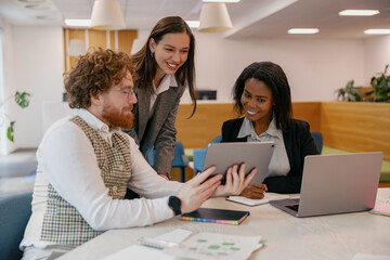 Three professionals engaging in a productive discussion using digital devices in a contemporary workspace.