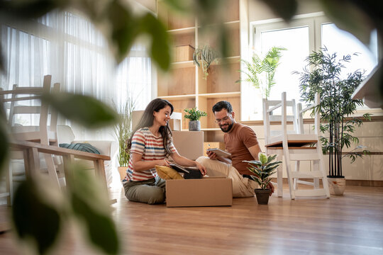 Happy couple unpacking boxes in new home after moving in