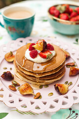 Fluffy pancakes with berries, whipped cream, and nuts. Served with warm milk tea for a sweet and cozy start to the day