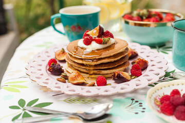 Fluffy pancakes with berries, whipped cream, and nuts. Served with warm milk tea for a sweet and cozy start to the day