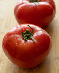 Close-up photo of a fresh, ripe tomato placed on a wooden cutting board