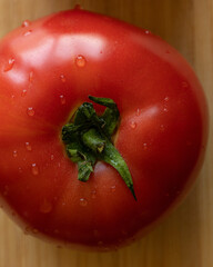 Close-up photo of a fresh, ripe tomato placed on a wooden cutting board