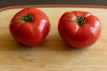 Close-up photo of a fresh, ripe tomato placed on a wooden cutting board