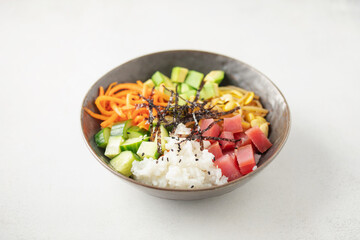 A traditional dish of Hawaiian cuisine. Poke bowl with tuna and vegetables in a bowl on the table