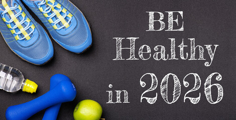 New year 2026 resolutions healthy lifestyle and sport. Be healthy in 2026. Motivation sport goals 2026 with sport equipment shoes, dumbbells, fruit and water bottle on black background