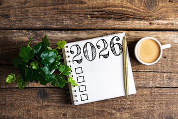 New year resolutions 2026 on desk. 2026 goals list with notebook, coffee cup, plant on wooden table. Resolutions, plan, goals, action, checklist, idea concept. New Year 2026 resolutions, copy space