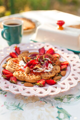 Heart-shaped waffles topped with berries and whipped cream. A cheerful brunch moment with a child enjoying the treat