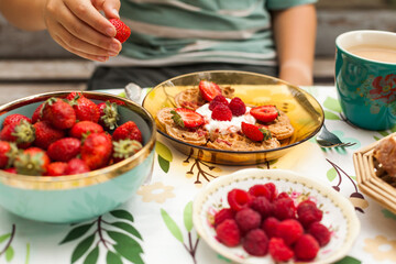 Heart-shaped waffles topped with berries and whipped cream. A cheerful brunch moment with a child enjoying the treat