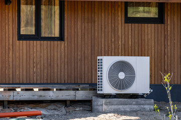 Air conditioning system in a modern frame house. Air conditioner compressor installed on the wall...