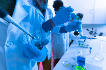 Scientists working with pipettes and beakers in laboratory research experiment