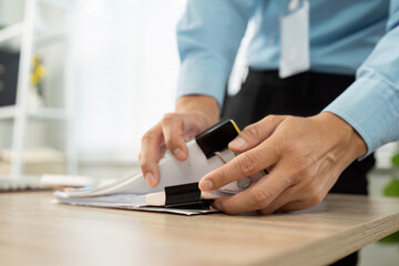 Office Productivity. Businessman organizing documents with a stapler at a modern workspace.