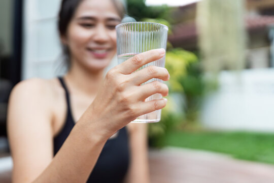 Wellness and Hydration. Young woman enjoying a refreshing glass of water outdoors.