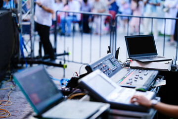 Professional audio and lighting control station at an outdoor event. Digital mixers, laptops, and...