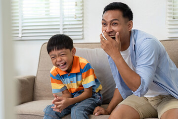 Joyful Moments in Gaming. Father and son laughing together while watching a video game.