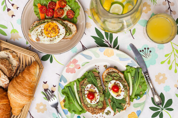 Rustic avocado toasts on oval bread served for a cozy family brunch with orange juice, croissants,...